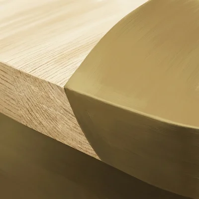 Close-up of a cabinet door panel's edge, where bare wood grain meets a fresh, even coat of aged-brass-toned paint along a clean line